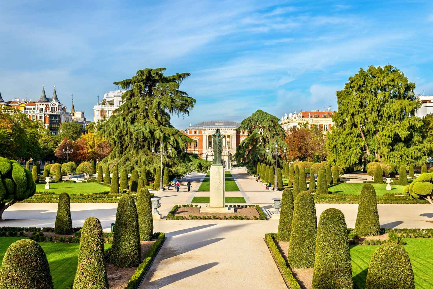 The verdant pathways of Madrid's Buen Retiro Park, with the Palacio de Velázquez in the distance