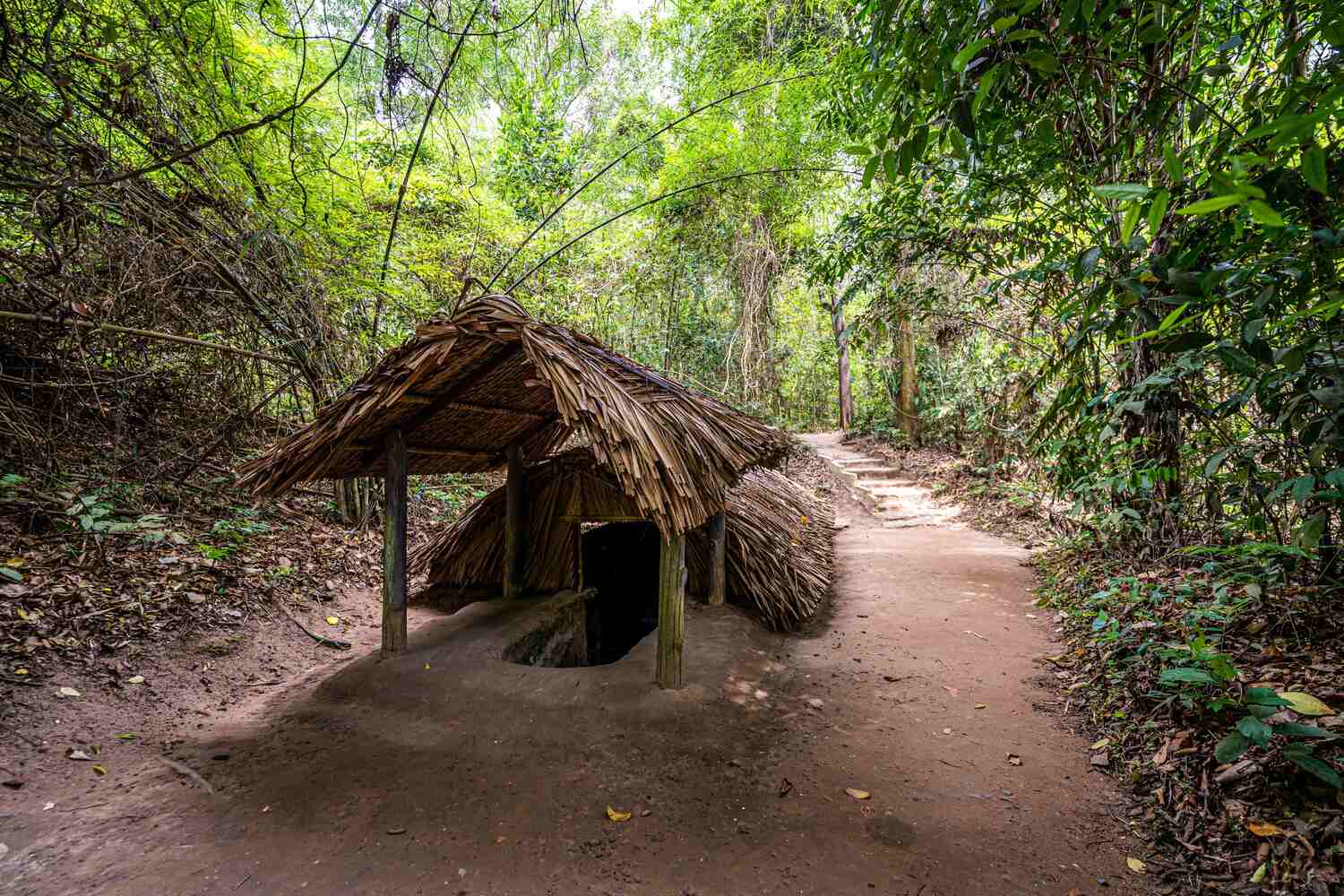 Rustic thatched hut along a jungle path in the Cu Chi tunnel complex area in Vietnam.