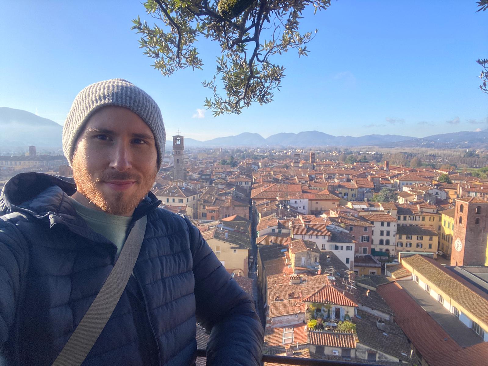 Man with cityscape of Lucca Italy in the background.
