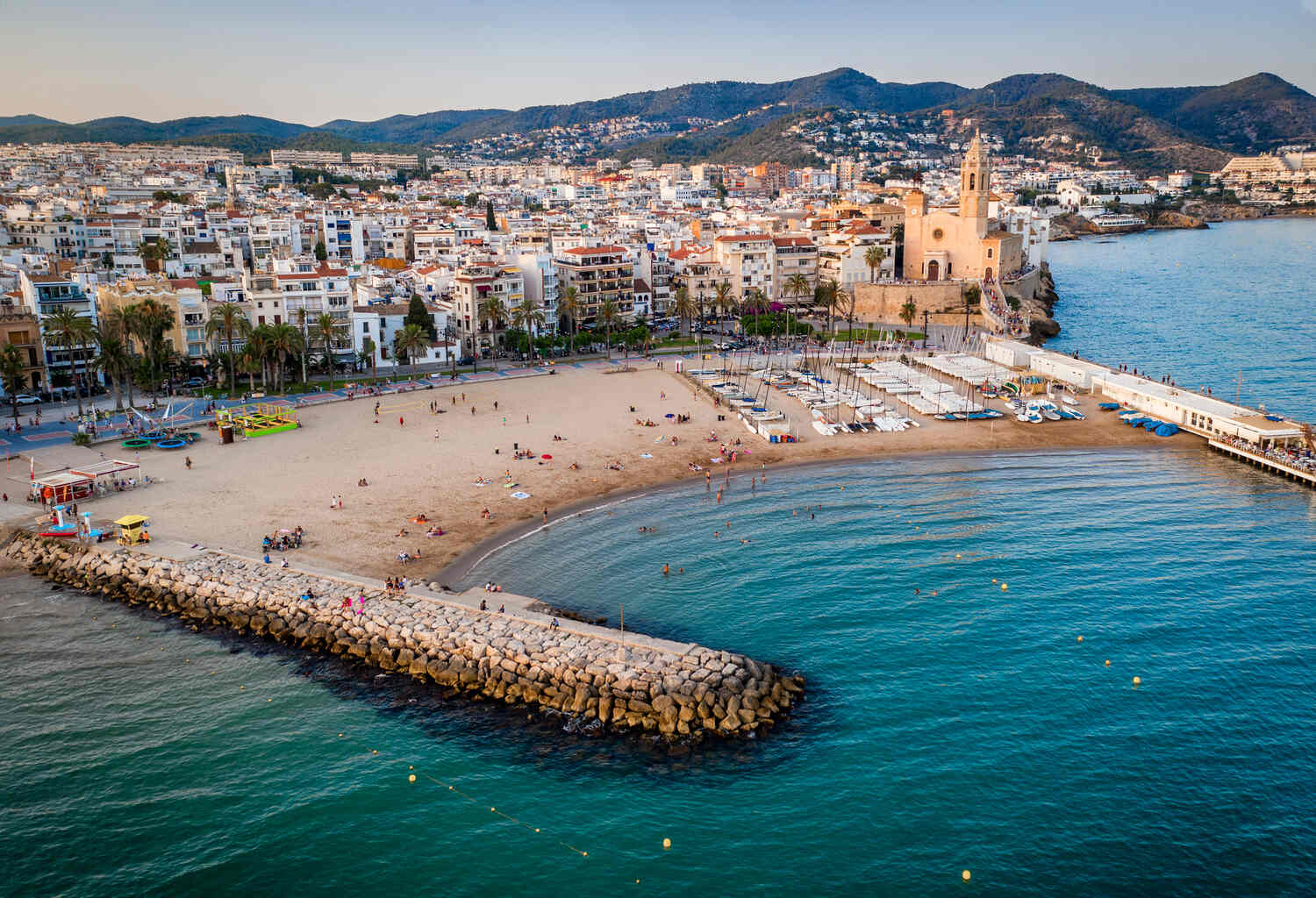 Curved beach of Sant Feliu de Guíxols in Spain, with clear waters and a view of the town.