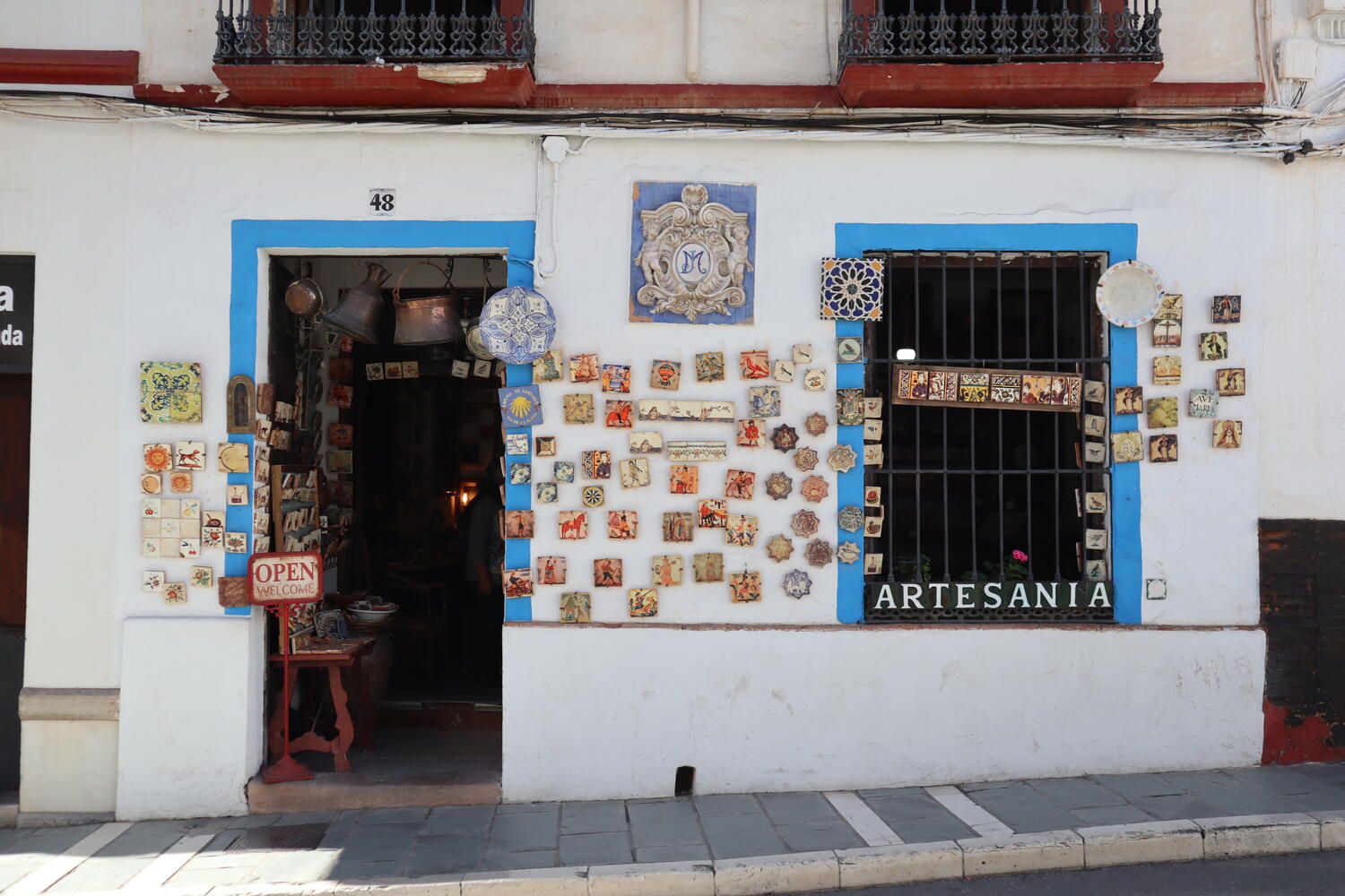 Colorful wall of ceramic plates outside a white-washed shop in Andalusia, Spain.