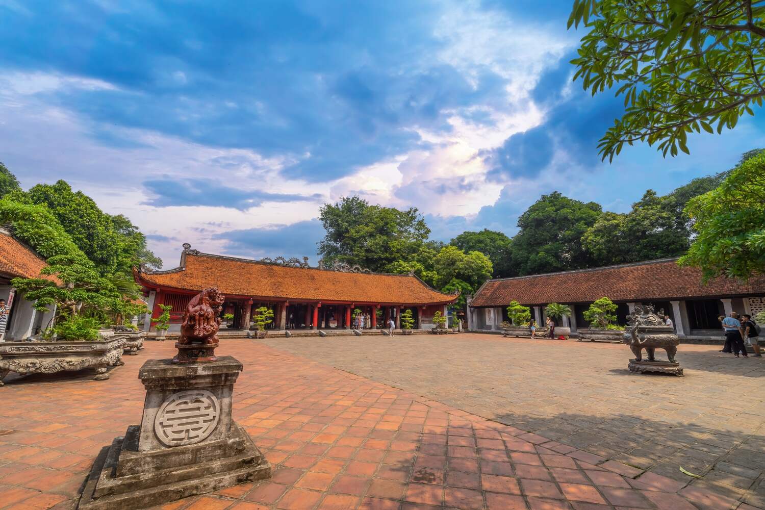 Expansive courtyard of the Temple of Literature, flanked by traditional Vietnamese architecture under a cloudy sky.