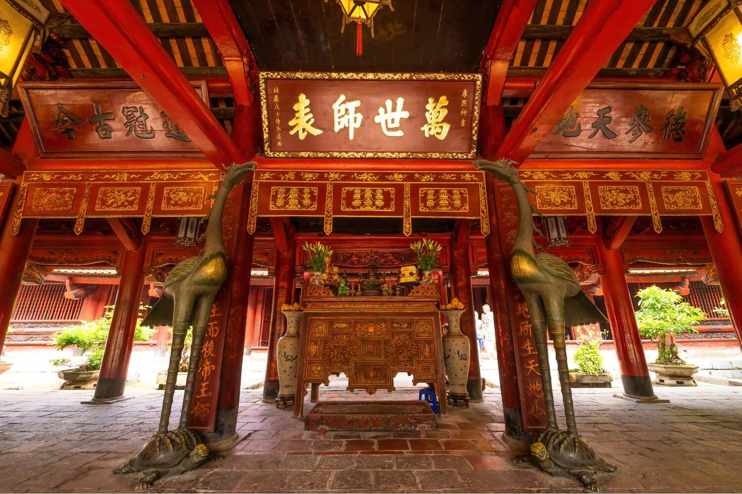 Intricate altar and ornate wooden beams inside the historic Temple of Literature in Hanoi.