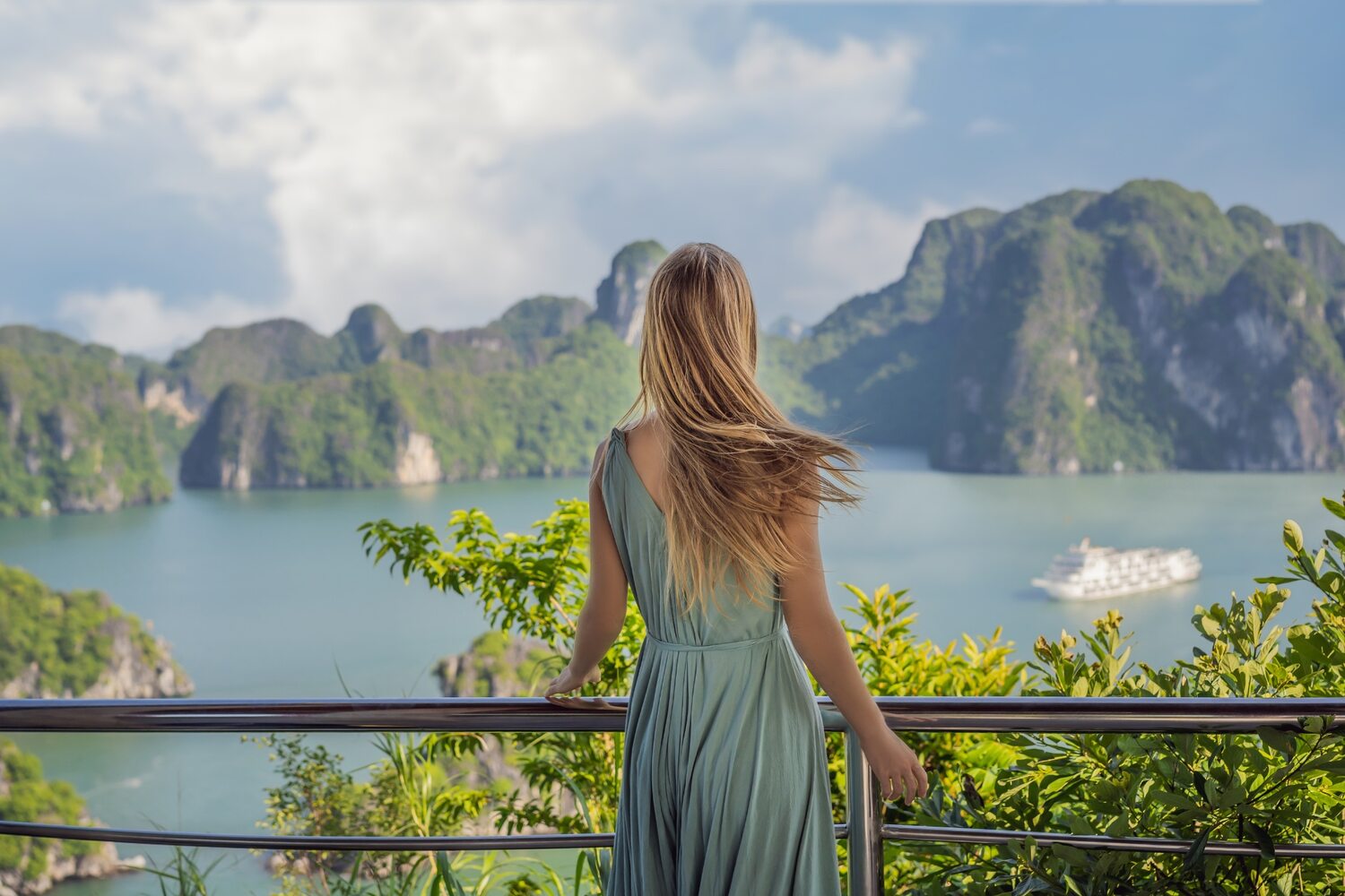 Woman gazing at the majestic limestone karsts of Ha Long Bay from a scenic overlook.