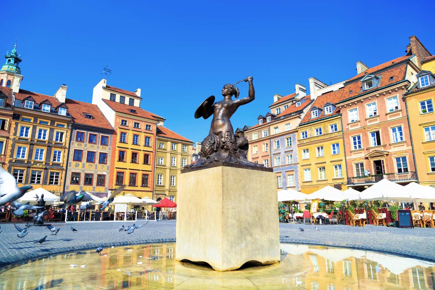 A vibrant market square with a crowd of people and historic colorful buildings in Warsaw.