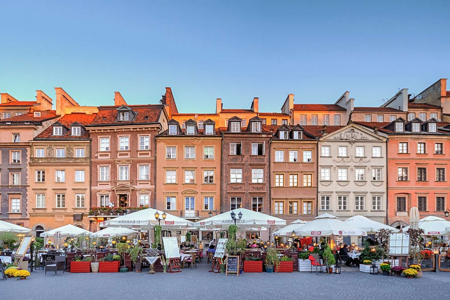 Brown and beige buildings on a big square with lots of restaurants in Warsaw, Poland